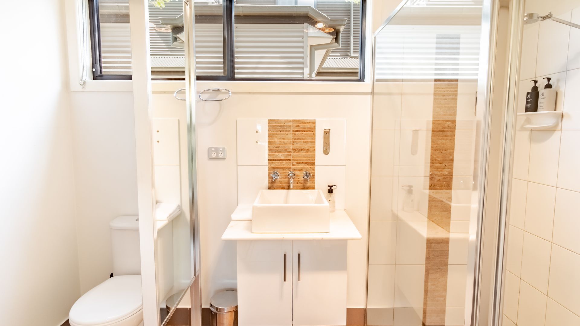 A modern bathroom with a glass-enclosed shower, a white sink, and a toilet.