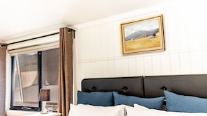 A hotel room with a bed, a window with curtains, a bedside table with a lamp, and a framed picture on the wall. - ALLAMBIE COTTAGES - VILLA 2: Bright (Bright)