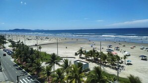 Une plage bordée de palmiers, avec des parasols, et une route au premier plan.