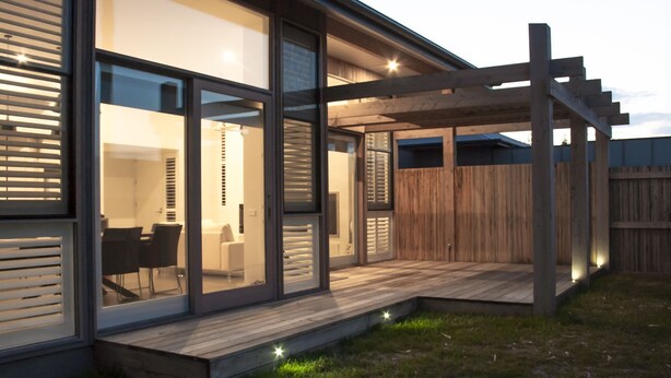 A modern house with large glass windows, a wooden deck, and a covered outdoor area. - Barwon Heads beach and river - great location. Flexible cancellation (Barwon Heads)