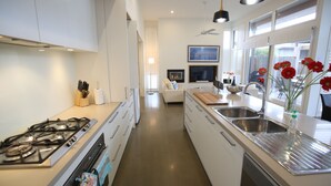 A modern kitchen with white cabinets, stainless steel appliances, and a central island with a sink. - Barwon Heads beach and river - great location. Flexible cancellation (Barwon Heads)