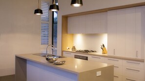 A modern kitchen with a central island, stainless steel appliances, and pendant lighting.