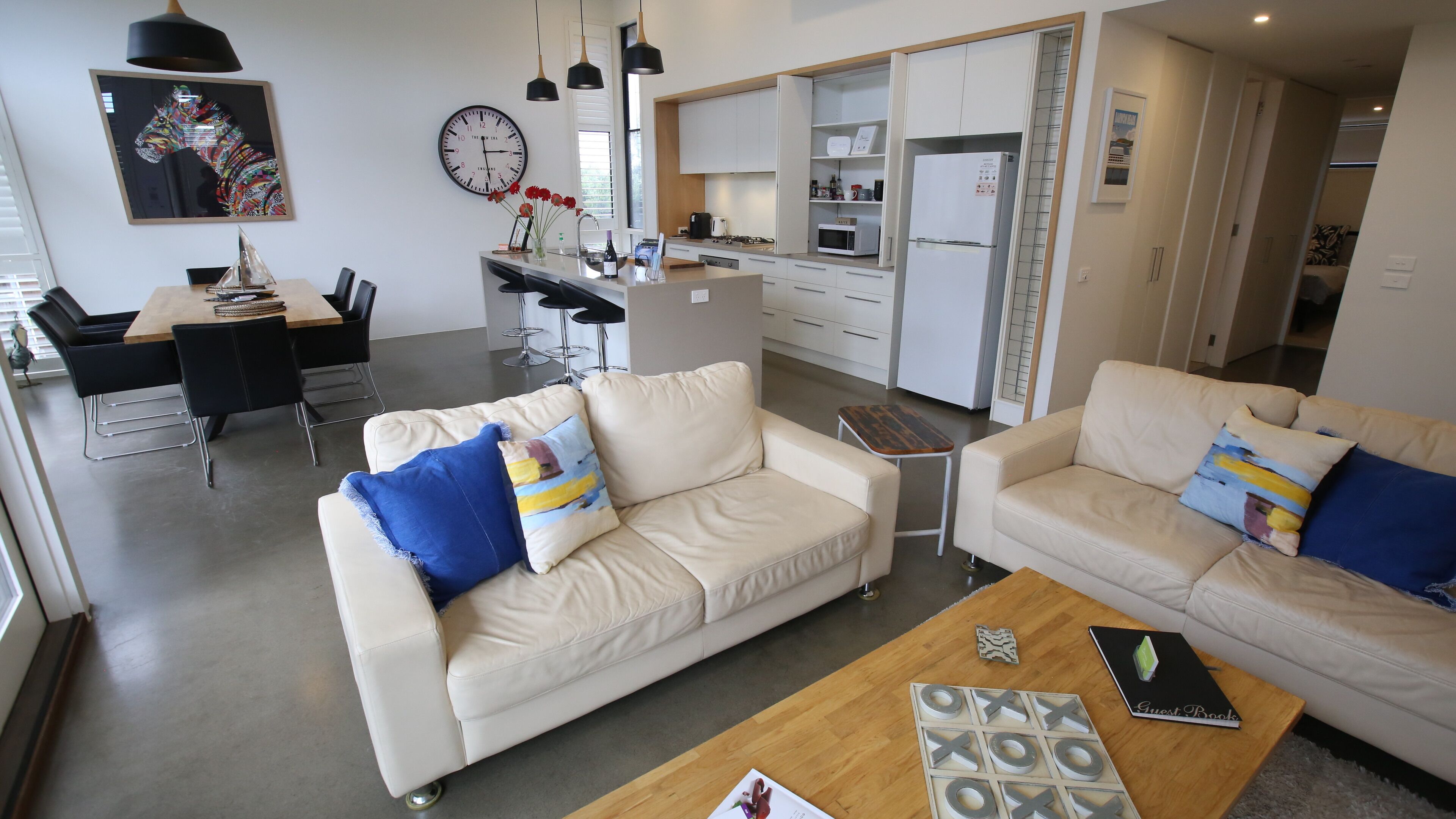 Een moderne woonkamer met twee banken, een salontafel en een eethoek met een tafel en stoelen.