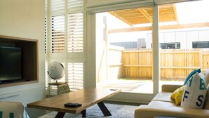 A living room with a TV, a globe, a wooden table, and a sofa with pillows. - Barwon Heads beach and river - great location. Flexible cancellation (Barwon Heads)