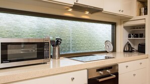 A kitchen with a microwave, a kettle, and a clock on the counter.