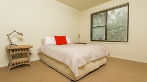 A bedroom with a bed, a nightstand, a lamp, and a window.