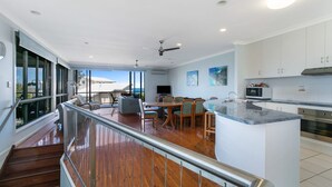 A spacious kitchen with a central island, a dining area with chairs, and a staircase leading to an upper level.