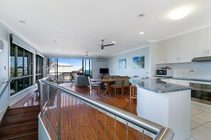 Enjoy meals in the kitchen with a central island and dining area, featuring a range hood, microwave, and large windows offering a view of the outdoors.