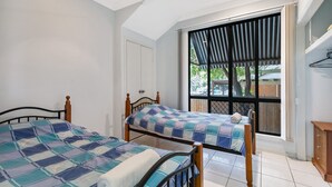 A bedroom with two beds, a window with a view of the outdoors, and a ceiling fan.