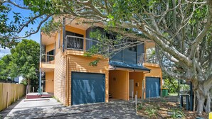 A two-story building with a balcony on the upper floor, a garage door, and a wooden deck leading to the entrance.
