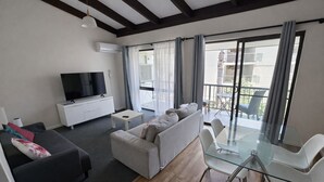 Ein modernes Wohnzimmer mit einer Couch, einem Fernseher und einem Glastisch.