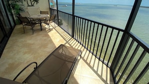A balcony with a table and chairs, a ceiling fan, and a view of the ocean. - Sanibel Harbour Resort Harbour Tower 716:          Private beach, heated pool, and grill (Fort Myers)