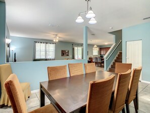 Enjoy meals in this dining area with a large table and six chairs, surrounded by a modern ceiling fan and pendant lighting.
