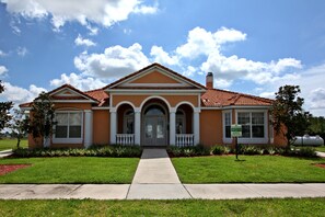 Stunning two-story building with a central entrance, flanked by windows and a decorative archway, set amidst a beautifully manicured lawn.