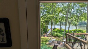 A deck with a view of a lake, surrounded by trees and a wooden pathway. - Lakefront- Rhode Island; Indian Lake, Wakefield : 223 Indian Trail S. (Wakefield)