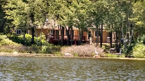 A lakeside property with a wooden deck and a building with a balcony. - Lakefront- Rhode Island; Indian Lake, Wakefield : 223 Indian Trail S. (Wakefield)