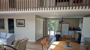 A spacious living area with a dining table, sofas, and a kitchen in the background. - Lakefront- Rhode Island; Indian Lake, Wakefield : 223 Indian Trail S. (Wakefield)