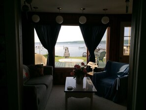 Relax in a serene lakeside retreat with a sofa, chair, and stunning view of the lake from a dock.