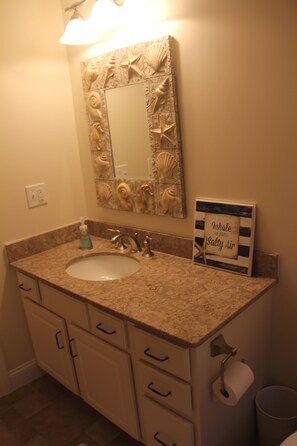 A bathroom with a sink, mirror, and decorative wall. There is a sign that reads "Inhale the Secret Salty Air." - Designer Home in Mashpee with central A/C (Mashpee)