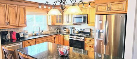 A kitchen with wooden cabinets, a stainless steel refrigerator, a microwave, and a gas stove.
