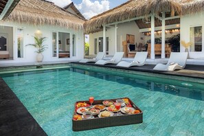 Una piscina al aire libre, sillones reclinables de piscina