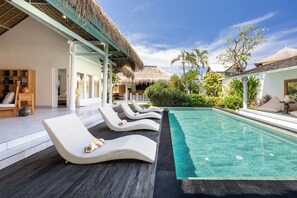 Una piscina al aire libre, sillones reclinables de piscina