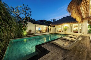 Una piscina al aire libre, sillones reclinables de piscina