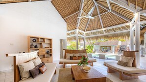 Un'ampia zona giorno con soffitto alto, arredi in legno e vista su piscina e paesaggio esterno.