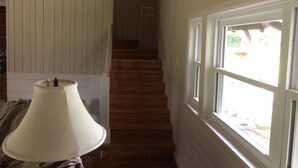 A staircase with wooden steps leading to a landing, a white lamp on a table, and a window with a view of greenery outside. - Shawano WI Wolf River home with lake access via Shawano Lake Channel (Shawano)