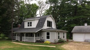 A two-story house with a porch, a garage, and a well-maintained lawn. - Shawano WI Wolf River home with lake access via Shawano Lake Channel (Shawano)