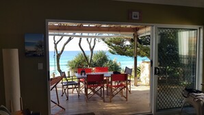 An open patio with a table and chairs, a view of the ocean, and a wooden deck. - Watson Street 1, 29, Currimundi (Currimundi)