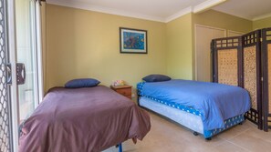 Een kamer met twee bedden, een klein nachtkastje met lamp, een schilderij aan de muur en een schuifdeur met decoratief paneel.
