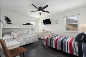 A bedroom with a bunk bed, a single bed, a desk, a chair, a TV, and a window. - 449 Ocean-Front Amazing Views & Easy Beach Access (Nags Head)