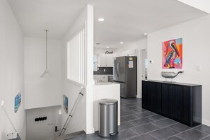 A modern kitchen with white cabinetry, a stainless steel refrigerator, and a black countertop.