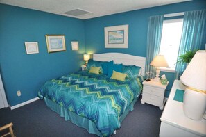 Une chambre à coucher avec un lit, des tables de chevet, une lampe et une fenêtre avec des rideaux.