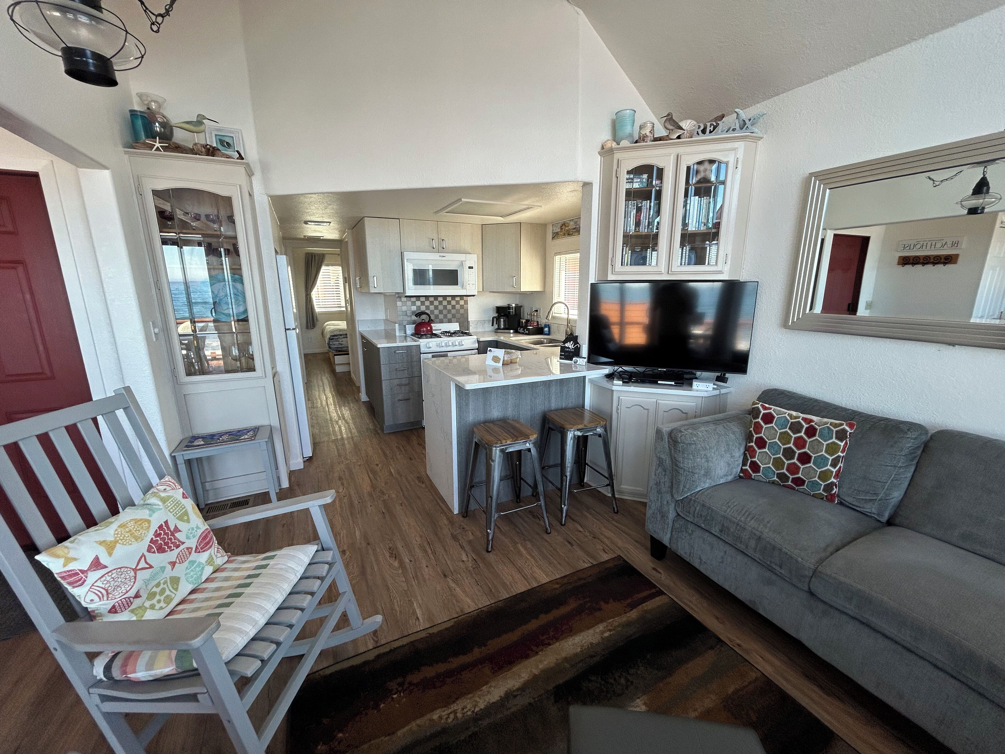 A compact living space with a kitchenette, a dining area, and a seating area with a sofa and a chair.