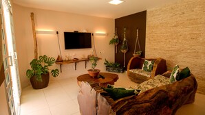 Een woonkamer met een bank, salontafel en hangplanten.