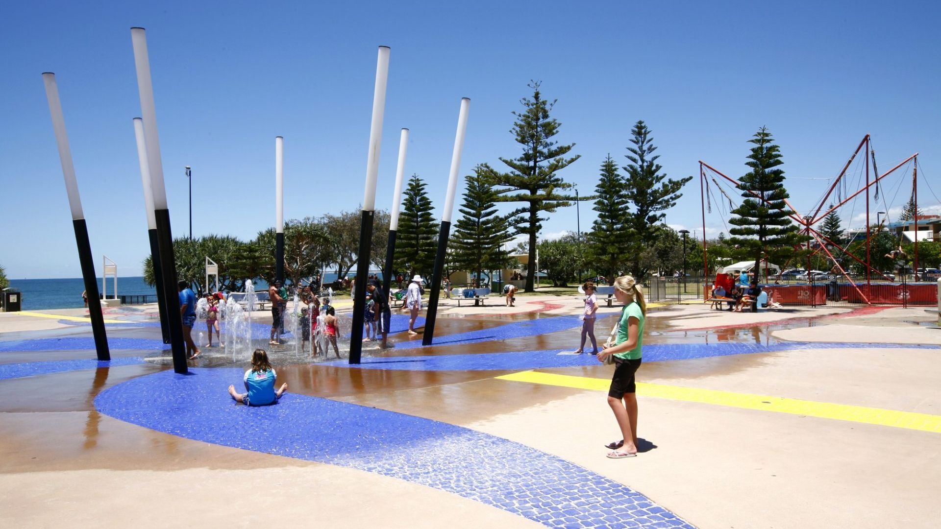 A water play area with multiple water jets and a sandy surface.