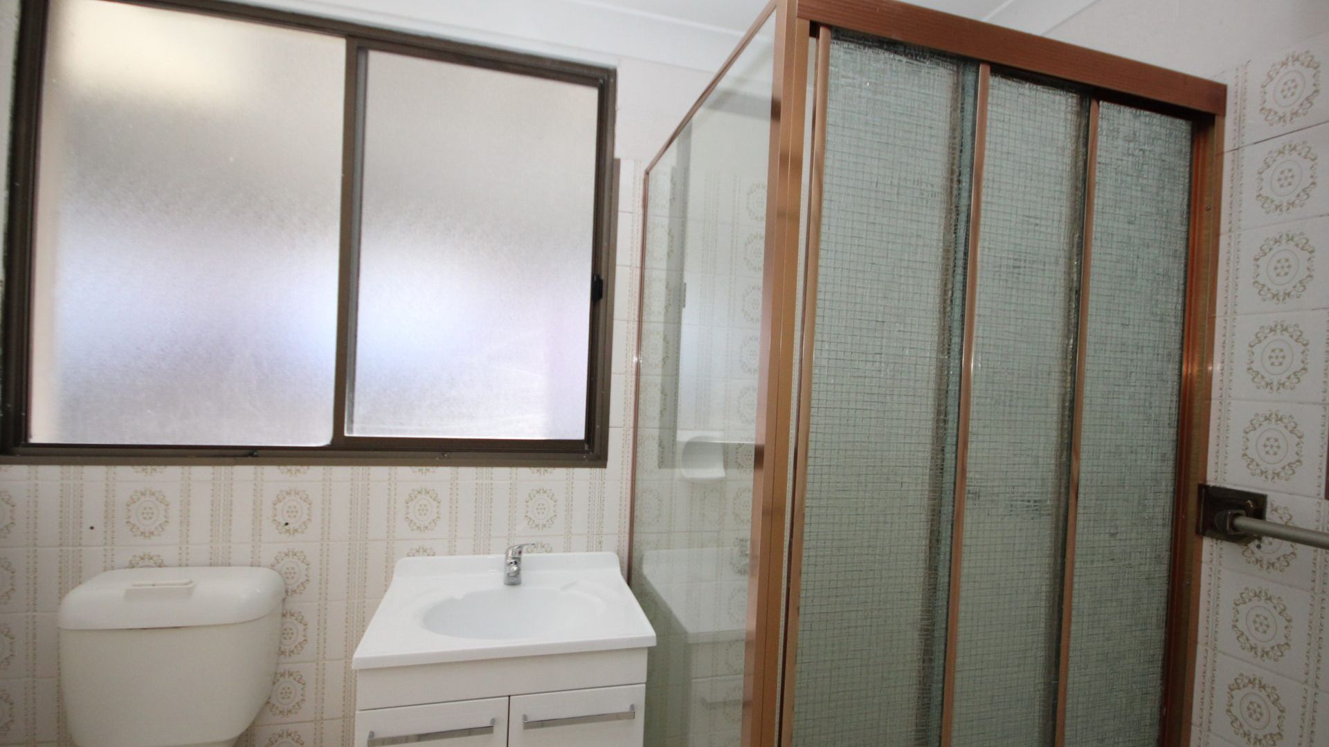 A bathroom with a toilet, sink, and shower with a glass door.
