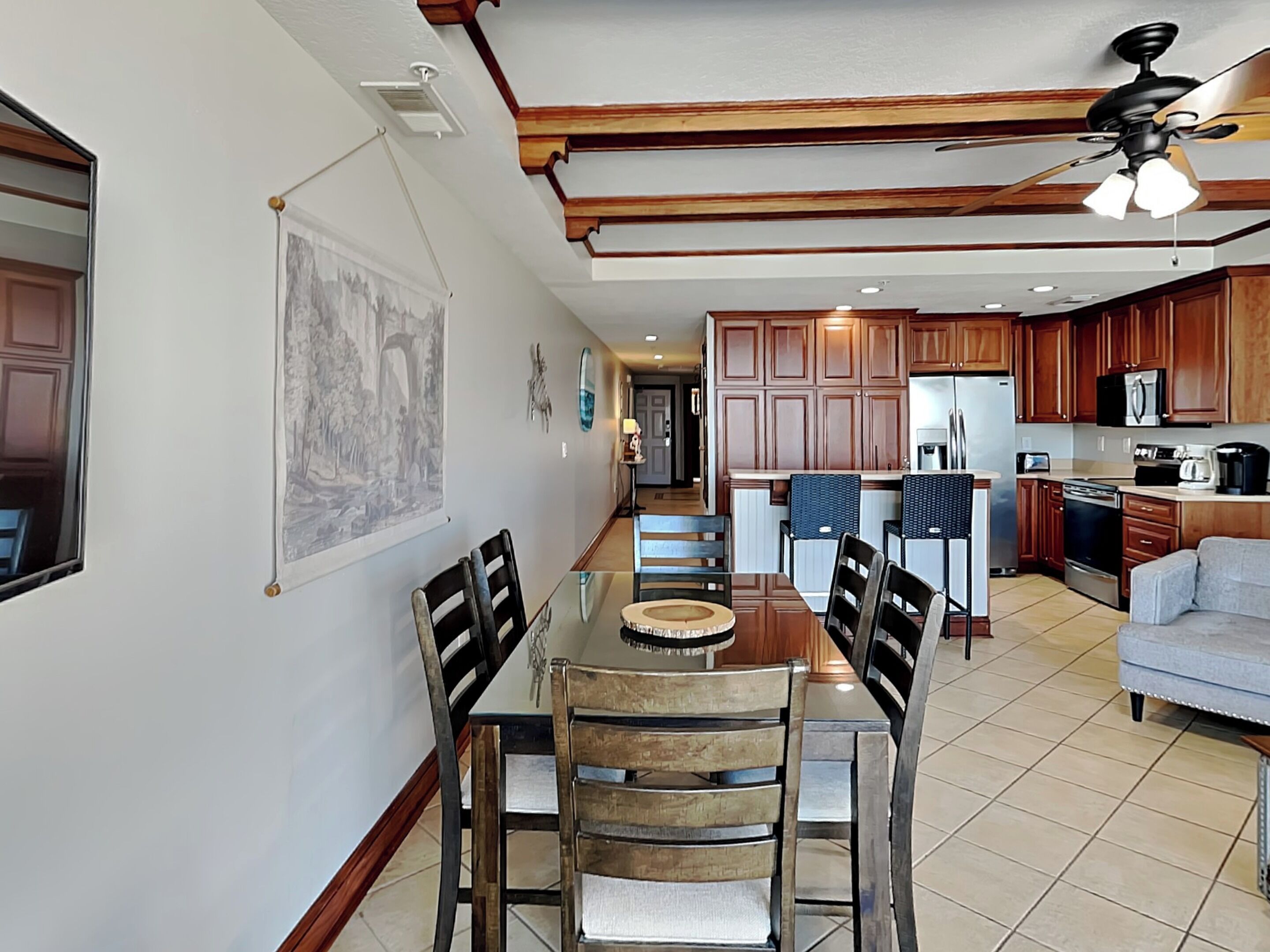 A spacious kitchen with wooden cabinets, a dining area with a glass table, and a ceiling fan.