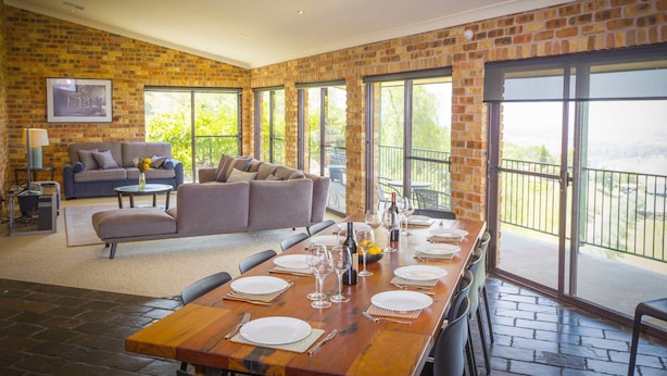 A spacious living area with a dining table set for six, a sofa, and a balcony with a view. - Aquila - 4 bedroom home with amazing valley views and swimming pool (Mount View)