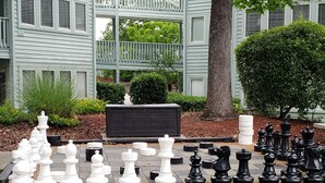 A chessboard set up outdoors with a large tree and a building in the background. - The Resort with it all - Beautiful Myrtle Beach Resort Condominium/FLEX Policies (Myrtle Beach)