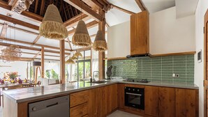 A modern kitchen with wooden cabinets, a dishwasher, and a green tiled backsplash.