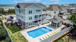 Une maison à deux étages avec un grand jardin, une piscine et une vue sur l’océan.
