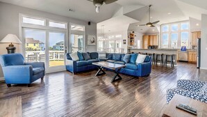 Een ruime woonkamer met een grote hoekbank, een salontafel en een eetgedeelte met barstoelen.