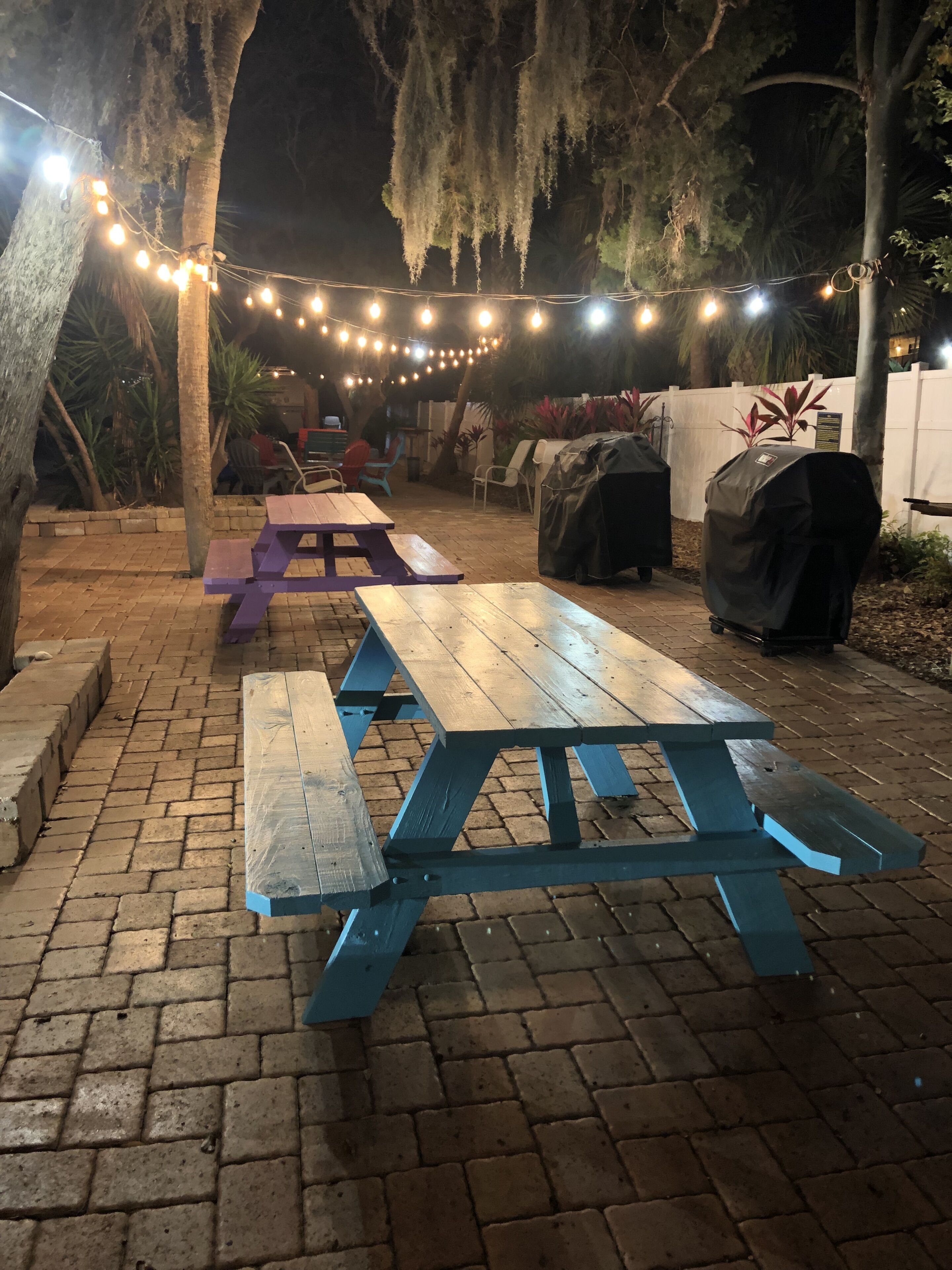 An outdoor patio area with picnic tables and string lights.