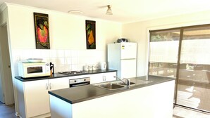 A modern kitchen with white cabinets, a stainless steel sink, and a built-in stove. - Al-Pac-Em Inn - Farm Stay (Kingscote)