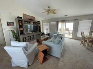 A living room with a television, white sofas, a wooden coffee table, and a ceiling fan. - Terrapin Station: Oceanfront Home for Vacation Rental, Pet Friendly, Sleeps 10 (Surf City)