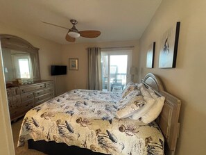 A bedroom with a bed, dresser, ceiling fan, and a balcony with a chair. - Terrapin Station: Oceanfront Home for Vacation Rental, Pet Friendly, Sleeps 10 (Surf City)