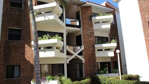 A multi-story building with balconies, brick walls, and a clear blue sky. - Atlantic One 2 Bedroom (Costambar)